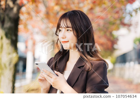 A woman going out during the autumn leaves season A woman going out during the autumn leaves season 107054634