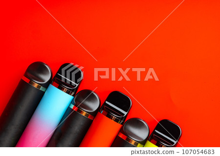 Colorful disposable electronic cigarettes on red background Colorful disposable electronic cigarettes on red background 107054683