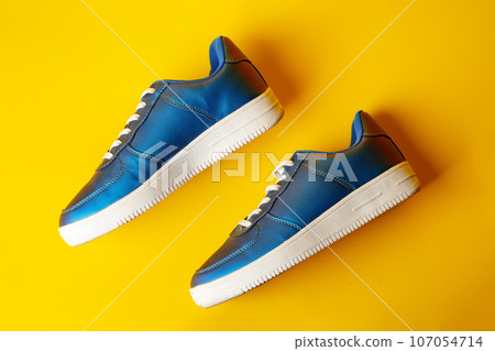Blue new sneakers on yellow studio background Blue new sneakers on yellow studio background 107054714