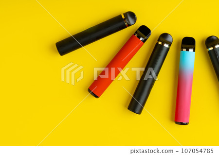Colorful disposable electronic cigarettes on yellow background Colorful disposable electronic cigarettes on yellow background 107054785