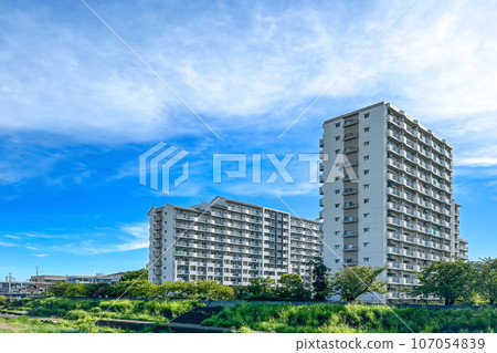 An apartment complex standing in the midst of nature, full of greenery, under the blue sky 107054839