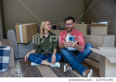 Young couple sitting on floor and resting after packing the containers 107055390