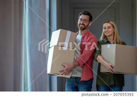 Young couple carrying cardboards with clothes while relocation Young couple carrying cardboards with clothes while relocation 107055391