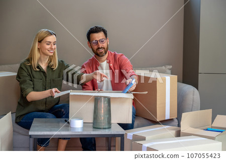 Young man and woman packing containers for relocation Young man and woman packing containers for relocation 107055423