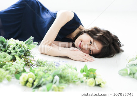 Young woman lying next to a bouquet of flowers 107055745
