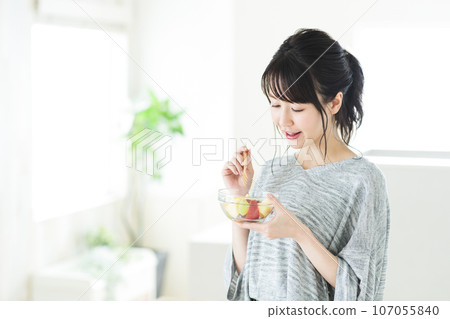 Young woman eating fruit salad in the living room 107055840