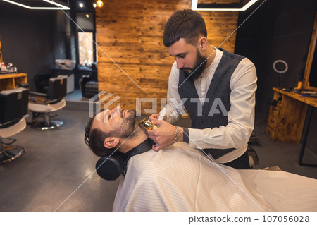 Caucasian man getting perfect shape of beard at barbershop. 107056028