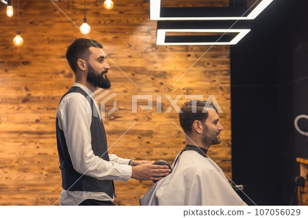 Man getting new trendy haircut or hairstyle with professional male barber. 107056029