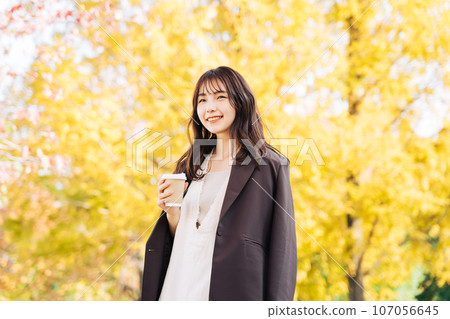 Woman drinking coffee under a ginkgo tree Woman drinking coffee under a ginkgo tree 107056645
