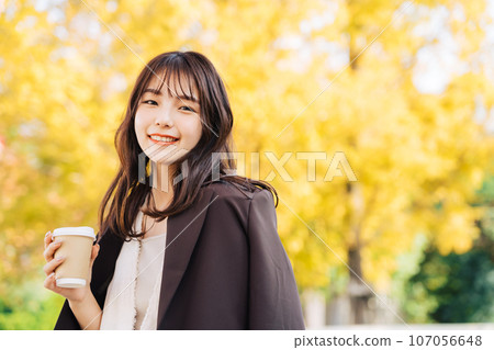 Woman drinking coffee under a ginkgo tree Woman drinking coffee under a ginkgo tree 107056648