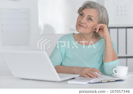 elderly woman working with a laptop on a white background elderly woman working with a laptop on a white background 107057346