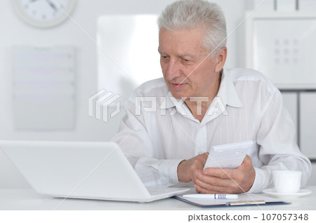 Senior businessman working with his laptop at office Senior businessman working with his laptop at office 107057348