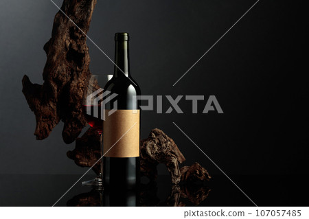 Red wine and old weathered snag on a black background. 107057485