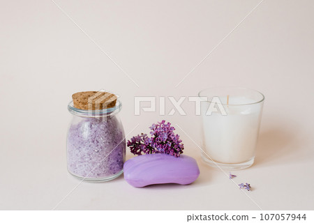 Cosmetic spa set for body care. Sea salt in a glass jar, organic soap, candle and lilac flowers on a light background 107057944