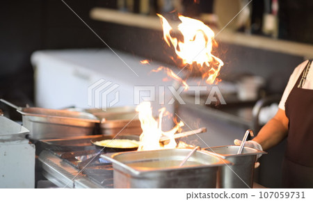 Cook is cooking on stove with an open fire 107059731