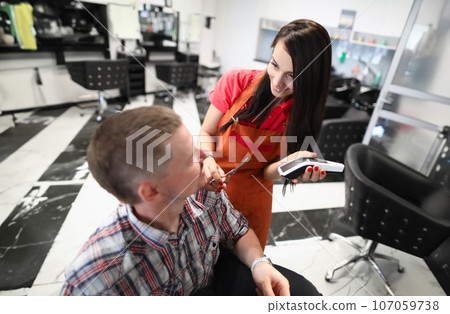 Woman hairdresser serves man in beauty salon 107059738