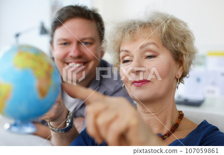 An elderly woman and young man looking at globe An elderly woman and young man looking at globe 107059861