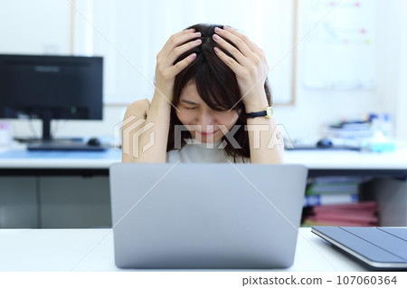 Image of a female office worker who is worried about holding her head 107060364