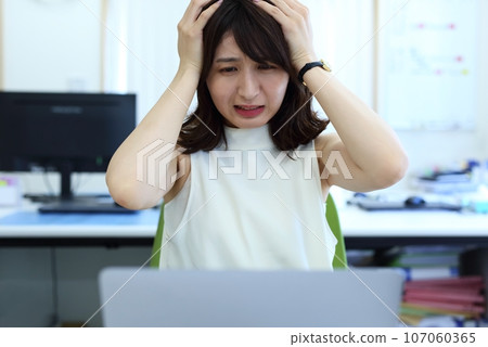 Image of a female office worker who is worried about holding her head 107060365