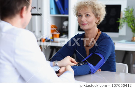 Doctor measures blood pressure of an elderly woman in medical office 107060412