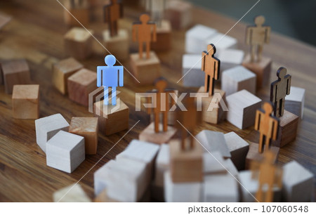 Wooden men on wooden cubes of brown color, one of them is blue 107060548
