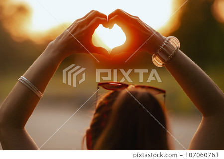 happy elegant woman in white shirt showing heart shaped hands 107060761