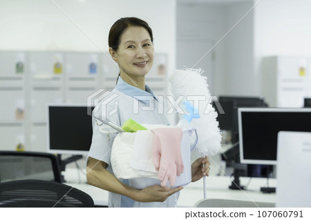 Portrait of a senior woman standing with cleaning tools in the office 107060791