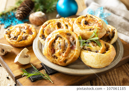 Pizza rolls puff pastry stuffed with prosciutto bacon, mushrooms and cheese on the Christmas table, italian appetizers. Pizza rolls puff pastry stuffed with prosciutto bacon, mushrooms and cheese on the Christmas table, italian appetizers. 107061185