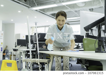 Senior woman wiping down her desk in the office 107061315