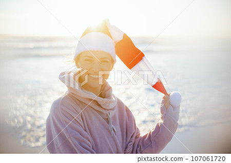 Portrait of happy female in cosy sweater at beach in evening 107061720