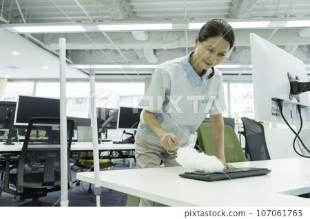 Female cleaner cleaning keyboard dust in office 107061763
