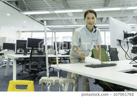 Female cleaner cleaning keyboard dust in office 107061768