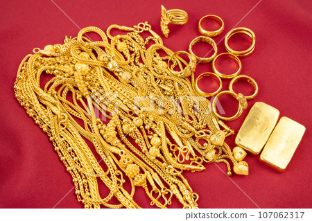 Many gold necklaces and gold bars on red velvet cloth. Many gold necklaces and gold bars on red velvet cloth. 107062317