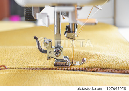 Modern sewing machine with yellow velours fabric close up 107065958