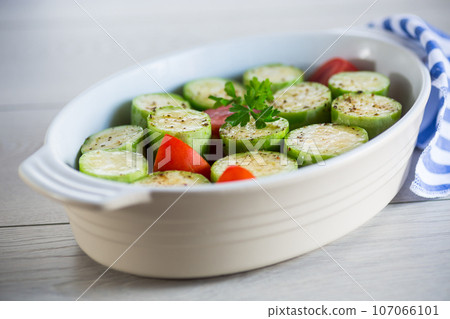 Raw zucchini with tomatoes prepared for baking in a ceramic form. Raw zucchini with tomatoes prepared for baking in a ceramic form. 107066101