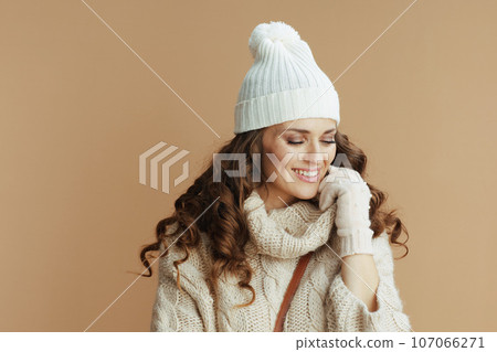 smiling stylish female in beige sweater, mittens and hat smiling stylish female in beige sweater, mittens and hat 107066271