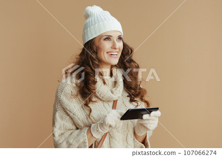 happy elegant woman against beige using phone applications happy elegant woman against beige using phone applications 107066274