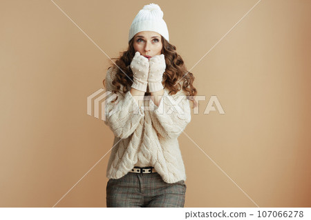 trendy woman against beige background warming hands trendy woman against beige background warming hands 107066278
