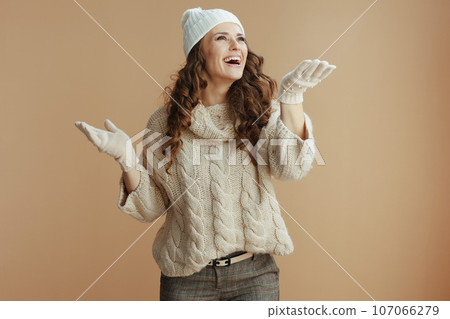 smiling stylish female isolated on beige catching snow 107066279