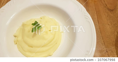 Mashed potatoes very delicious and creamy in a artistic white plate on wooden table background. Mashed potatoes very delicious and creamy in a artistic white plate on wooden table background. 107067998
