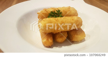 Breaded fried mozzarella cheese sticks plated in white plate served as appetizer or snack before main menu Breaded fried mozzarella cheese sticks plated in white plate served as appetizer or snack before main menu 107068249