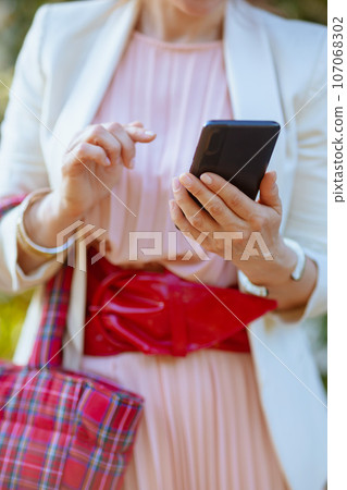 Closeup on woman in pink dress and white jacket in city Closeup on woman in pink dress and white jacket in city 107068302