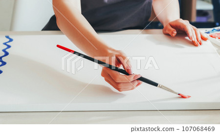 Art lesson. Painter leisure. Woman artist hands painting picture with brush red bright color oil dye on white canvas in studio. Art lesson. Painter leisure. Woman artist hands painting picture with brush red bright color oil dye on white canvas in studio. 107068469