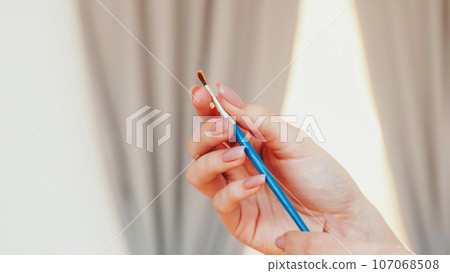 Artist brush. Painting tool. Unrecognizable woman hand with dirty wooden paintbrush bristle creative hobby in workshop studio. Artist brush. Painting tool. Unrecognizable woman hand with dirty wooden paintbrush bristle creative hobby in workshop studio. 107068508
