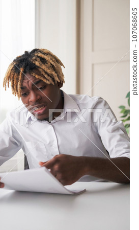 Documents problems. Business fail. Worried man reading graphics finding mistake checking report sitting at workplace light room interior. Documents problems. Business fail. Worried man reading graphics finding mistake checking report sitting at workplace light room interior. 107068605