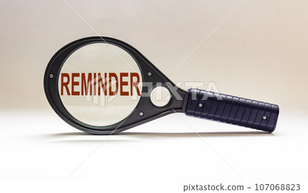 Reminder, text on magnifying glass and white background. Reminder, text on magnifying glass and white background. 107068823