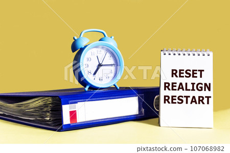 RESET, RESETTING, RESTART written on, notepad, next to document folder and clock. Business concept. 107068982