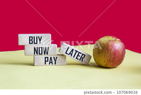On a red and yellow background, wooden blocks with the words BUY NOW, PAY LATER. On a red and yellow background, wooden blocks with the words BUY NOW, PAY LATER. 107069016