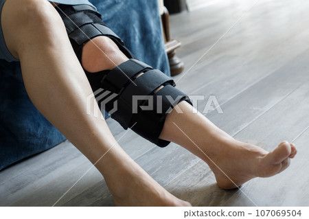 Patient wearing knee brace support after injury and surgery. Healthcare and medical concept. Patient wearing knee brace support after injury and surgery. Healthcare and medical concept. 107069504