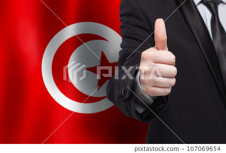 Tunisian concept. Businessman showing thumb up on the background of flag of Tunisia 107069654